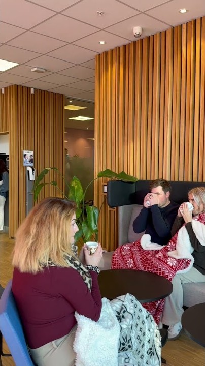 To kollegaer drikker kaffe med begge hendene under pledd