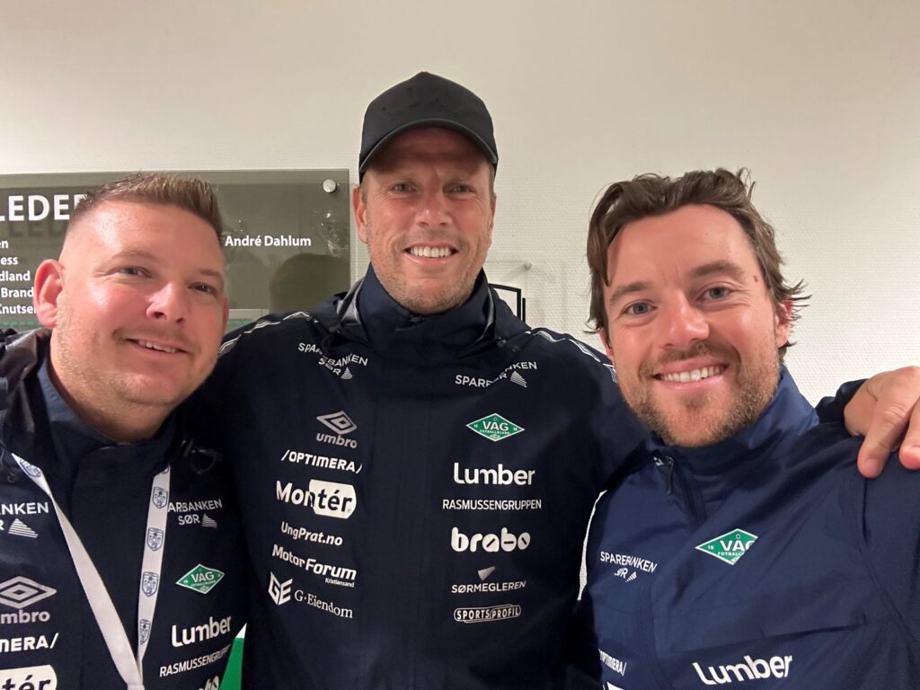 Tre menn i Våg-jakker smiler til kamera